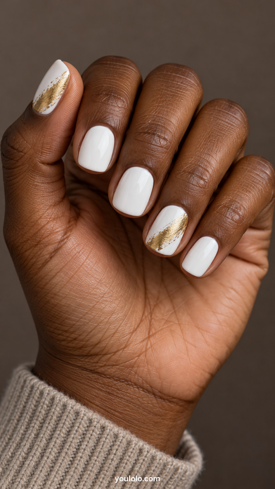Short squoval white nails with a feathered gold brush sweep on the ring nail and thumb