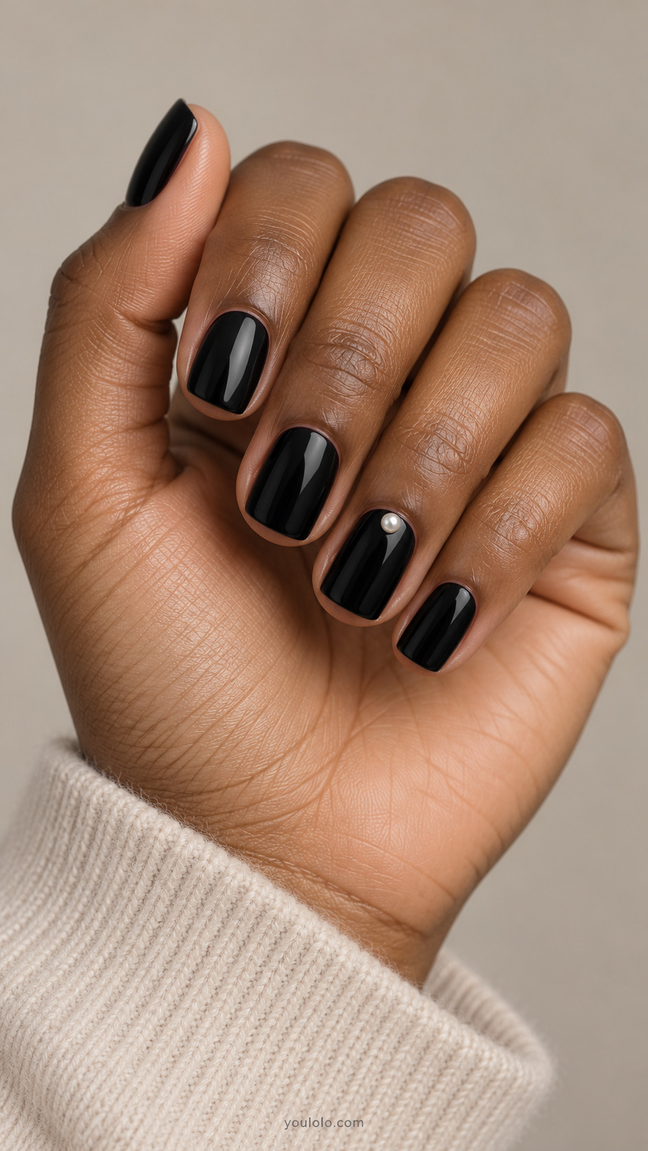 Short black nails with a single pearl near the ring nail cuticle