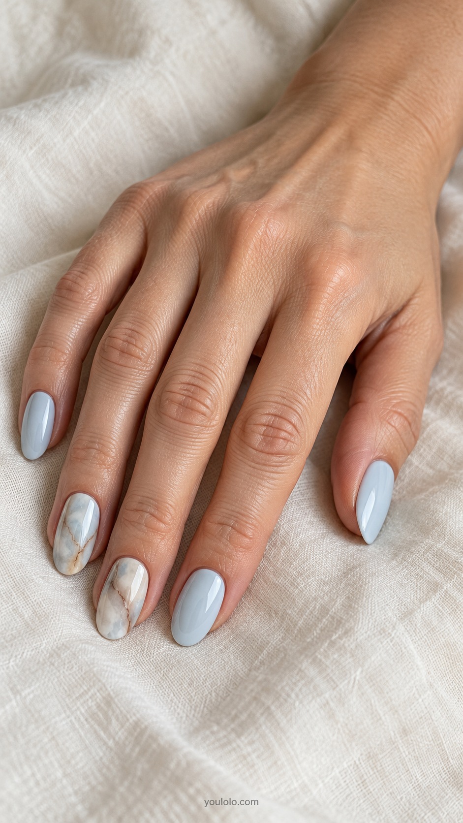 Pale Blue Brown Marble — medium oval pale blue base two ring and middle accent nails subtle brown and cream marble veining