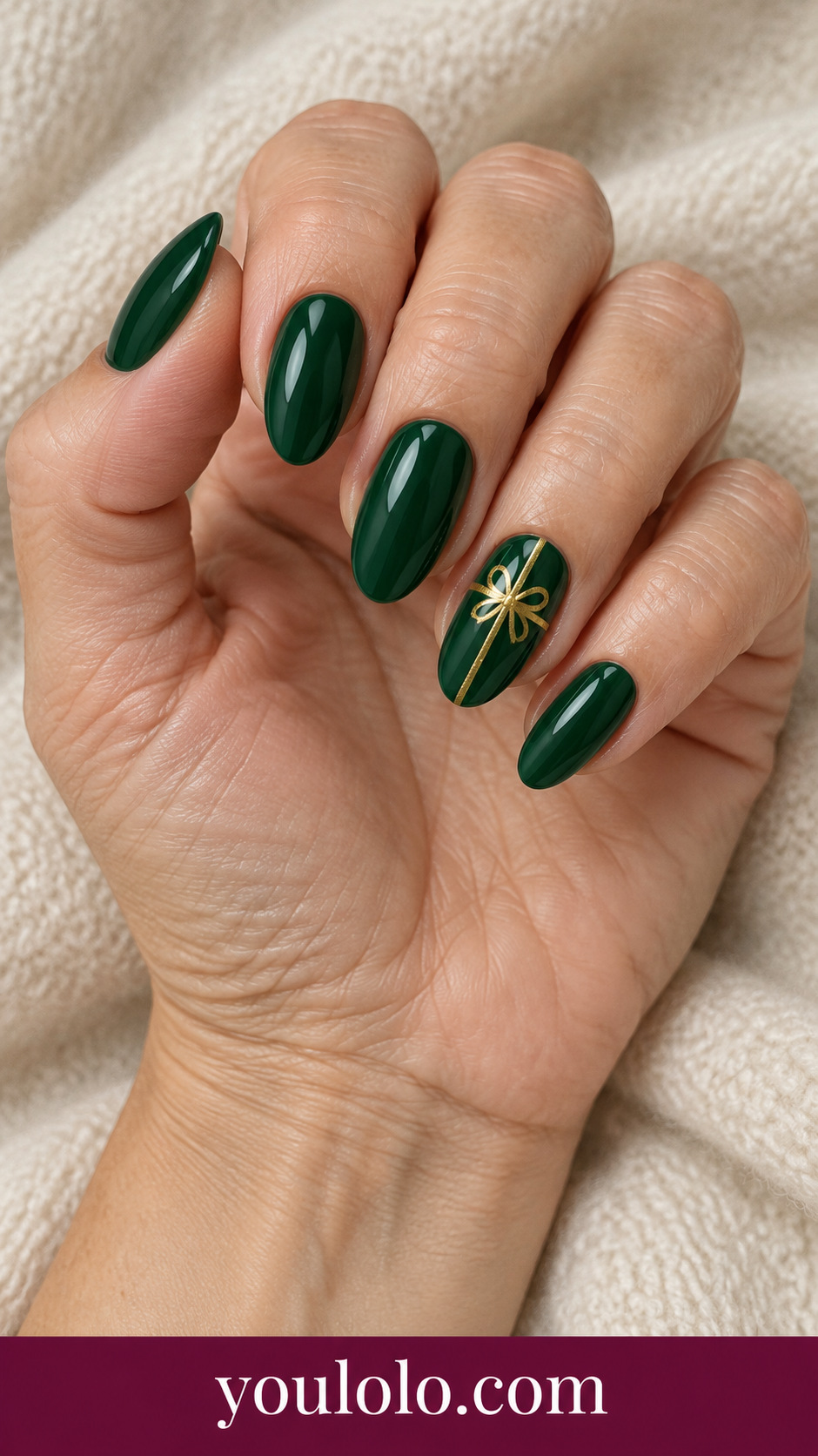 medium almond deep emerald press-on nails with single fine painted gold ribbon crossing ring nail like gift wrap, other nails plain green glossy on a naturally posed adult female hand