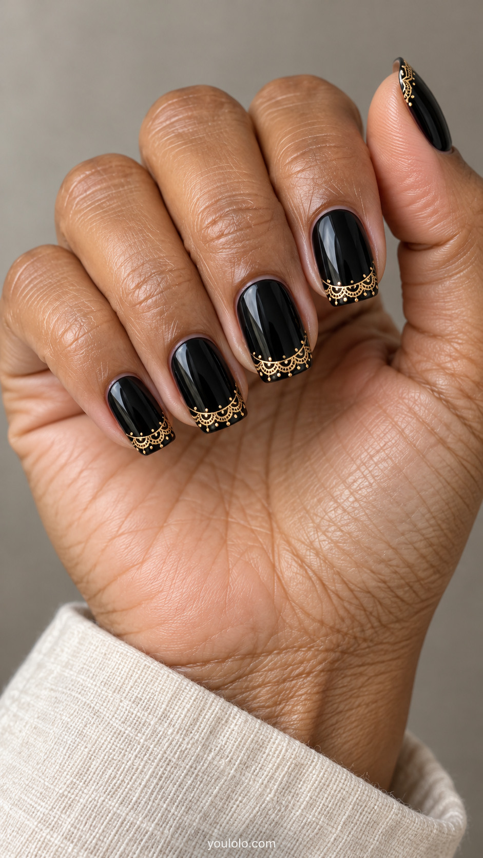 Black squoval nails with fine scalloped gold lace borders at the tips