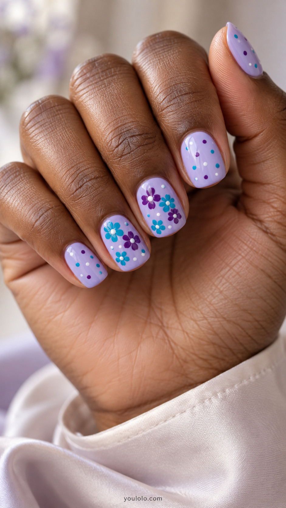 Short lilac nails with turquoise and plum dots and flower clusters.