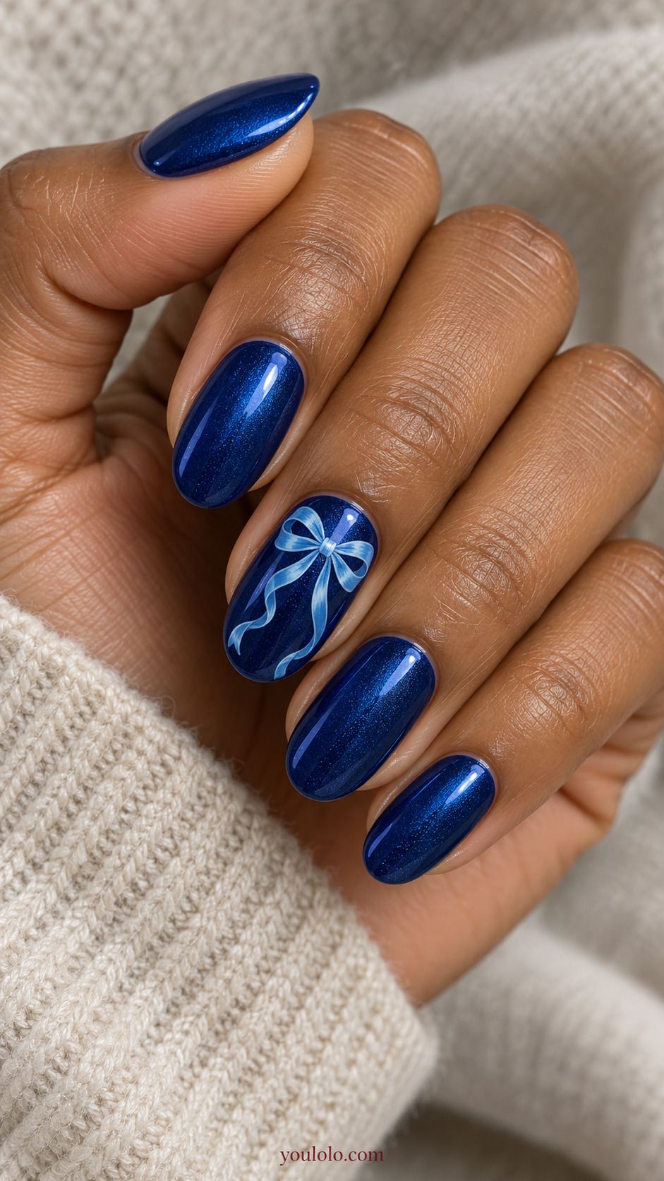Sapphire Ribbon Bow in Tonal Blue on a softly gathered feminine hand with detailed sapphire blue manicure