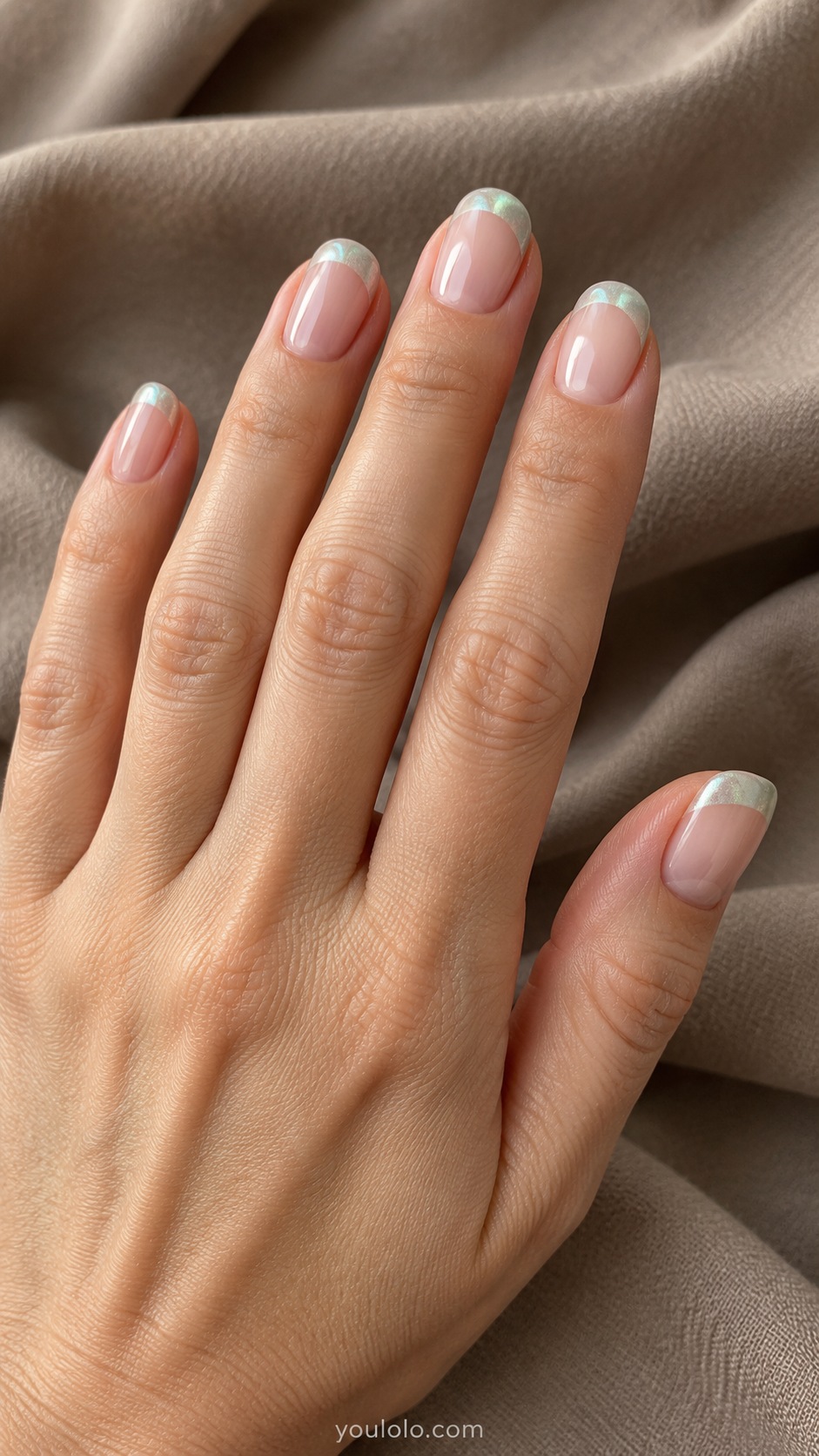 Short oval nails sheer beige pink base with muted pale seafoam green pearlescent French tips, base glossy but not pearl
