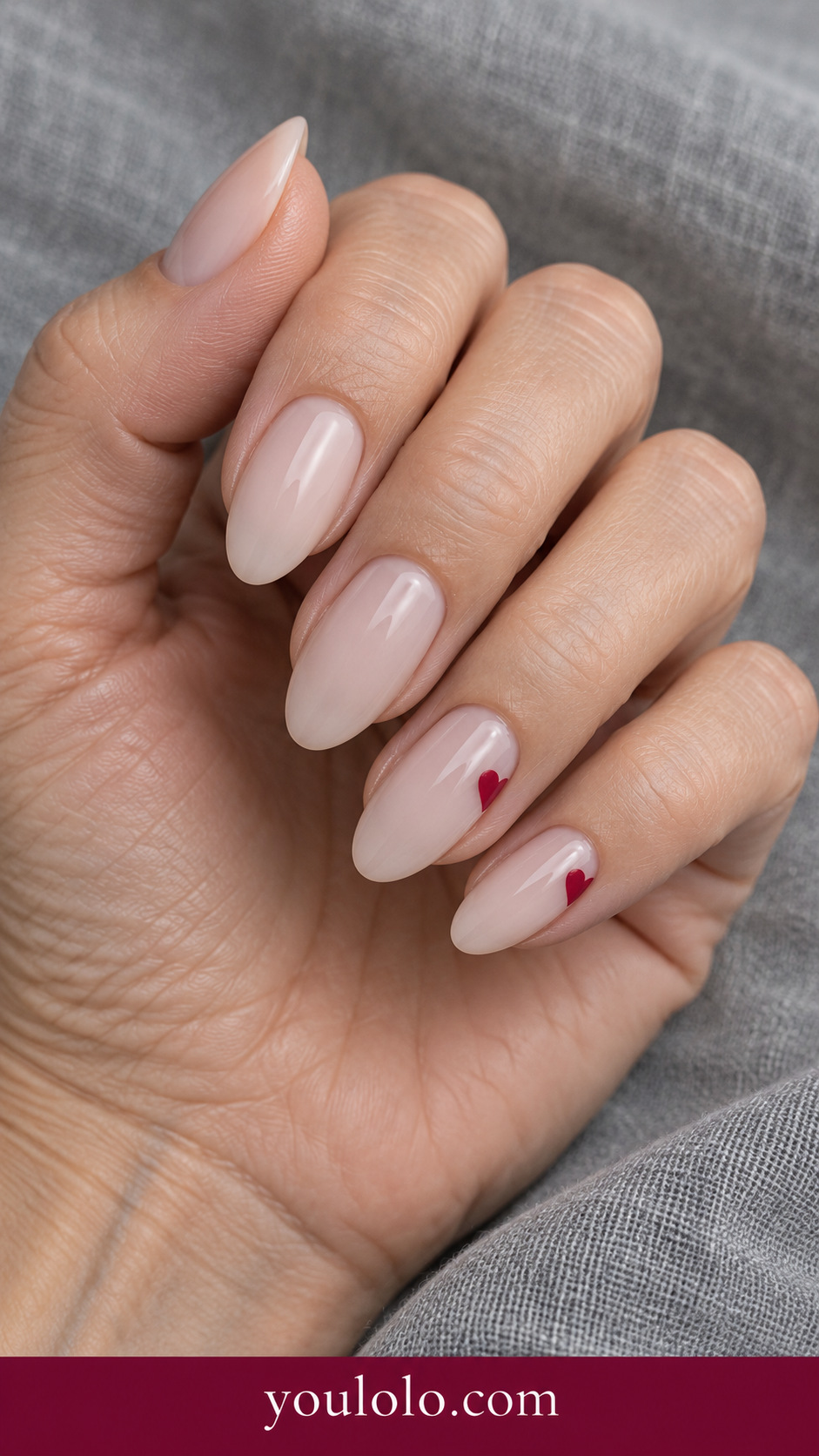 Heart Side Peek: medium almond sheer nude nails red heart silhouette partly peeking from one lateral edge on two nails on a naturally posed adult hand