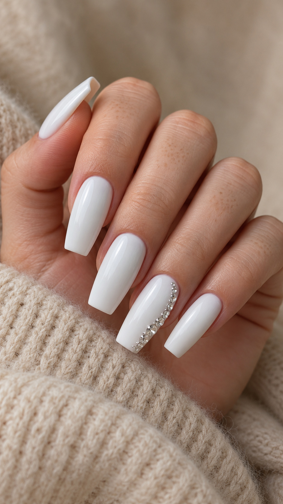 White Coffin Nails with a Crystal Side Border: Long white coffin nails with a graduated crystal row along one side of the ring nail on a naturally posed adult hand