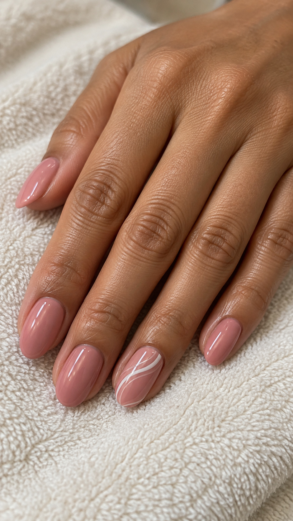 Pink with a White Swirl Accent: Rose pink oval nails with flowing white curves on the ring nail on a naturally posed adult hand