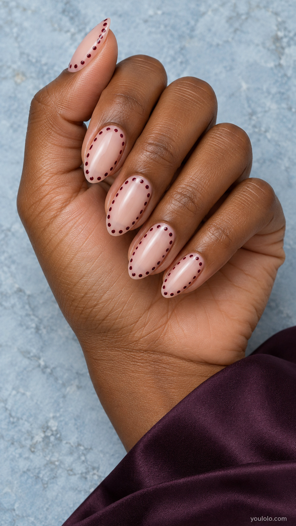 Medium almond translucent nude nails, small burgundy round dots trace entire perimeter set inside nail edge, centers perfectly clear.
