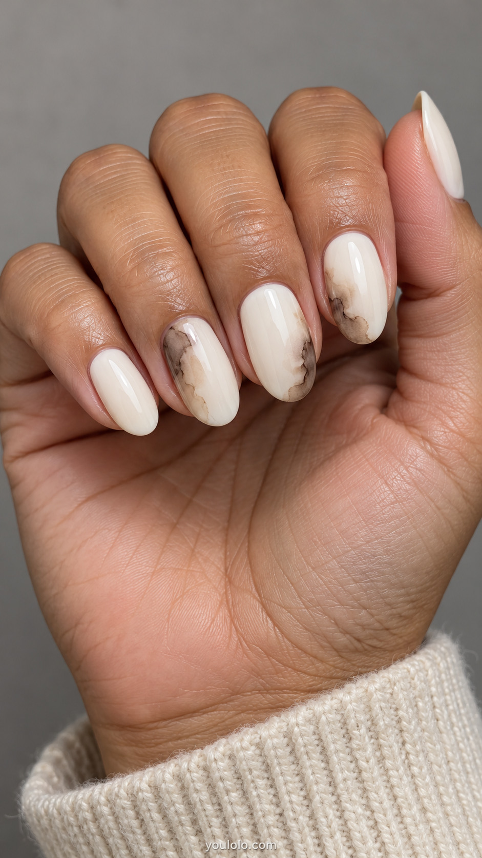 Medium oval nails: ivory nails with translucent smoky brown watercolor pools at random side edges on three accents, delicate soft-edged ink wash.