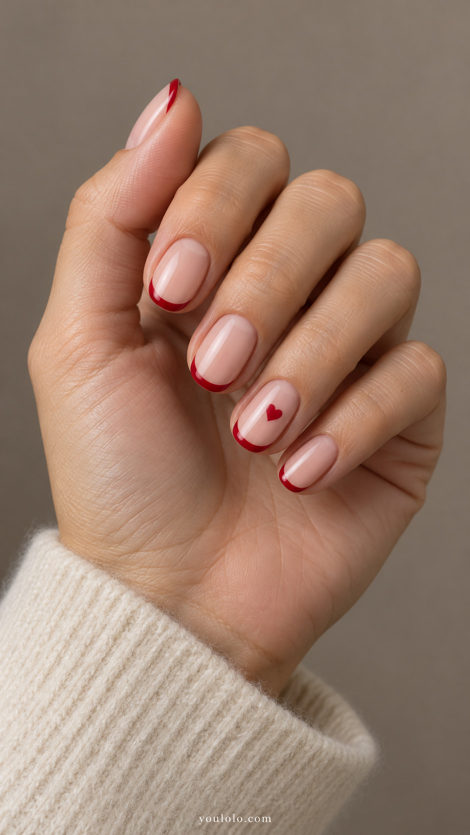 short oval blush nails, fine cherry-red French tips, one tiny painted red heart on ring nail center on a naturally gathered hand
