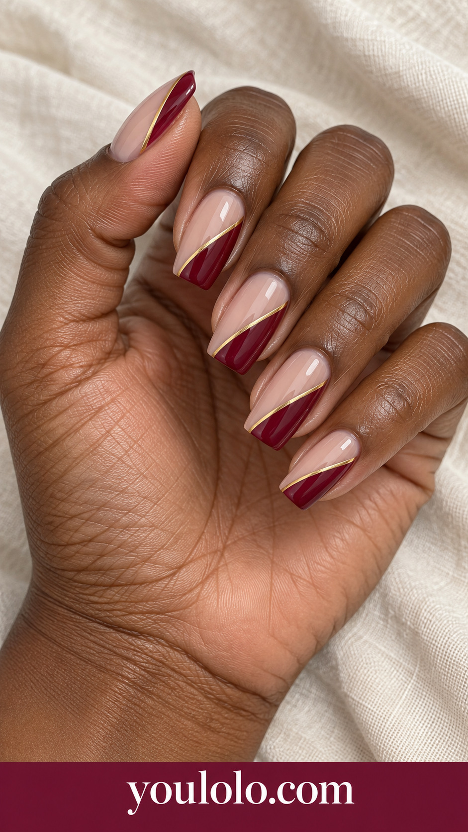 medium tapered square sheer warm nude press-on nails deep burgundy diagonal side panels with one fine gold separator, glossy on a naturally posed adult female hand