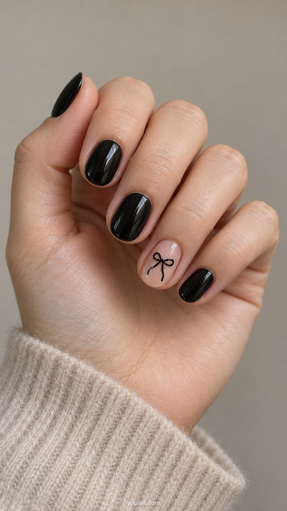 Black nails with a delicate black bow on a nude accent