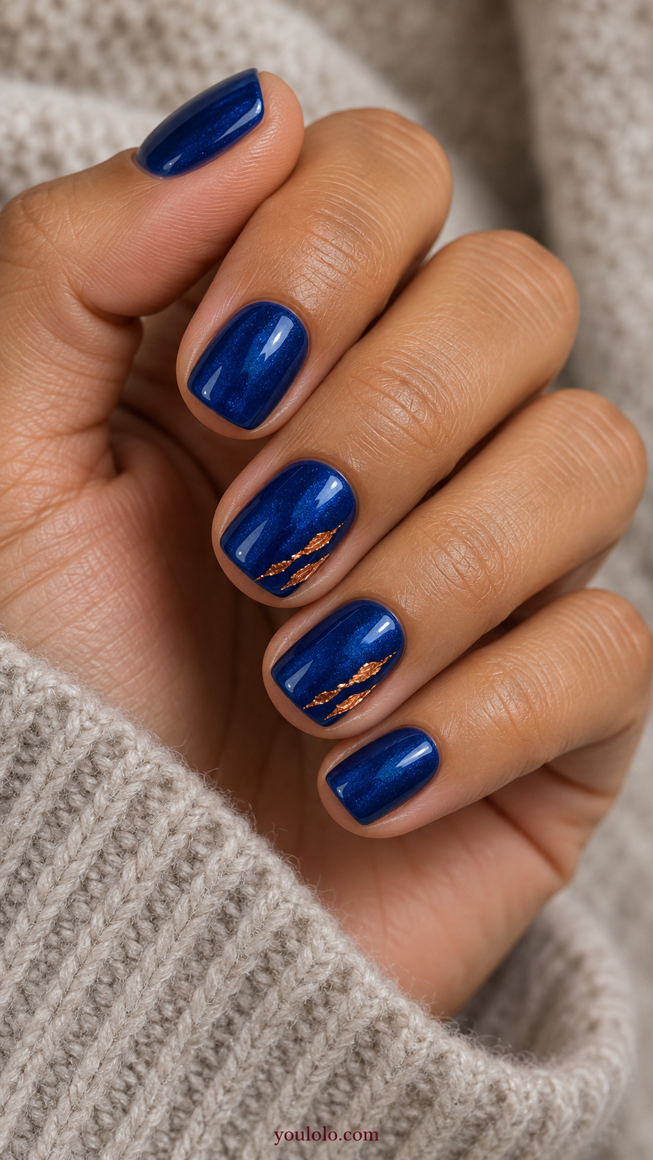 Sapphire with Copper Foil Slivers on a softly gathered feminine hand with detailed sapphire blue manicure
