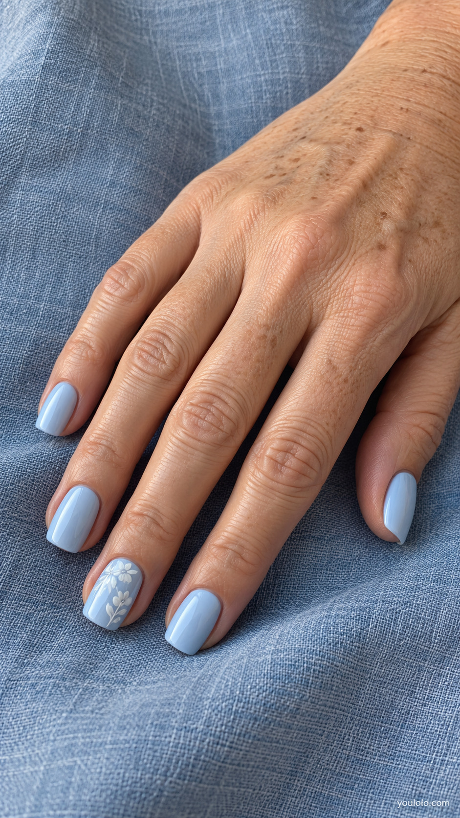 Powder blue square nails with white floral artwork on one nail