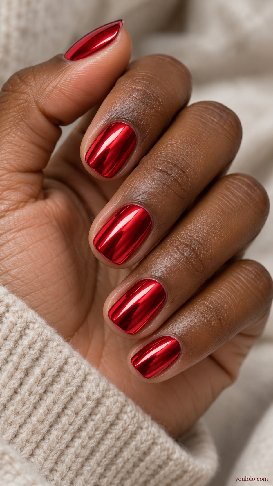 Very short cherry red mirror chrome nails on a softly gathered hand