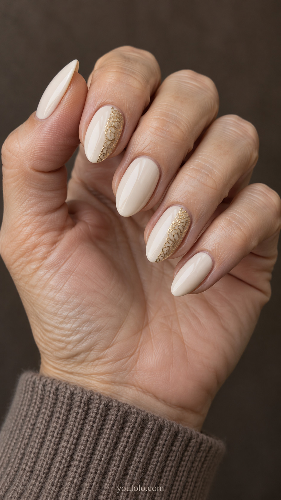 Medium almond ivory nails with narrow gold filigree panels along one side of two accent nails