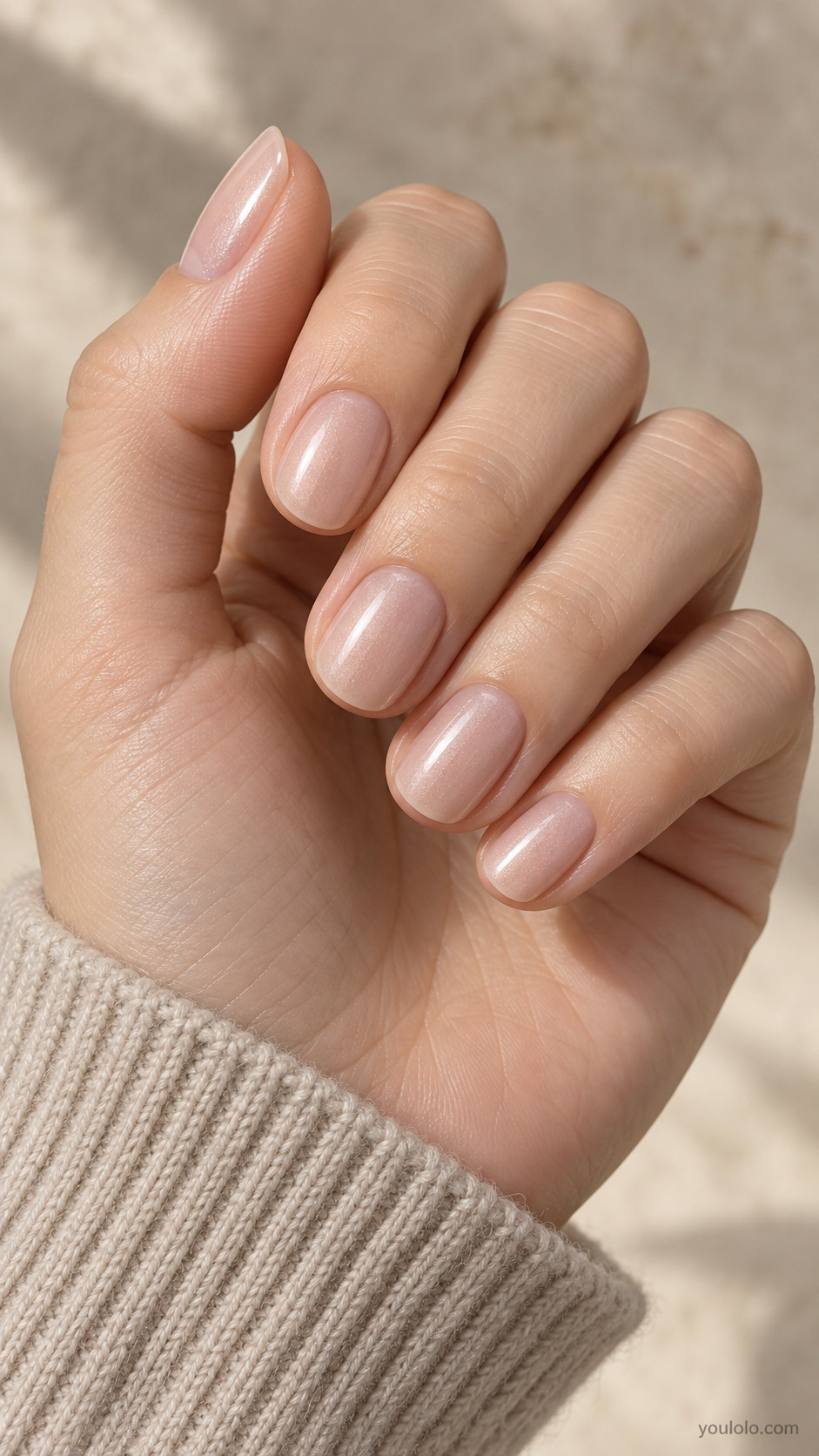 Short oval nails with sheer beige pink polish and a subtle pearlescent sheen.
