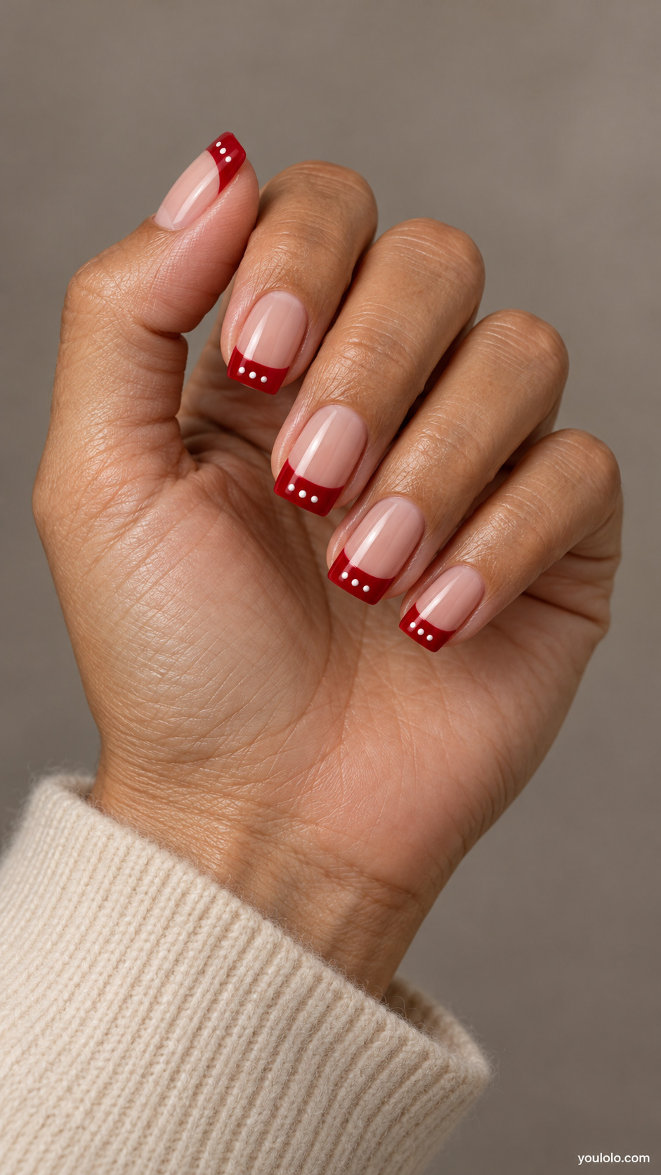 medium square nude nails, broad red French tips with three tiny white dots within red tip on each nail on a naturally gathered hand