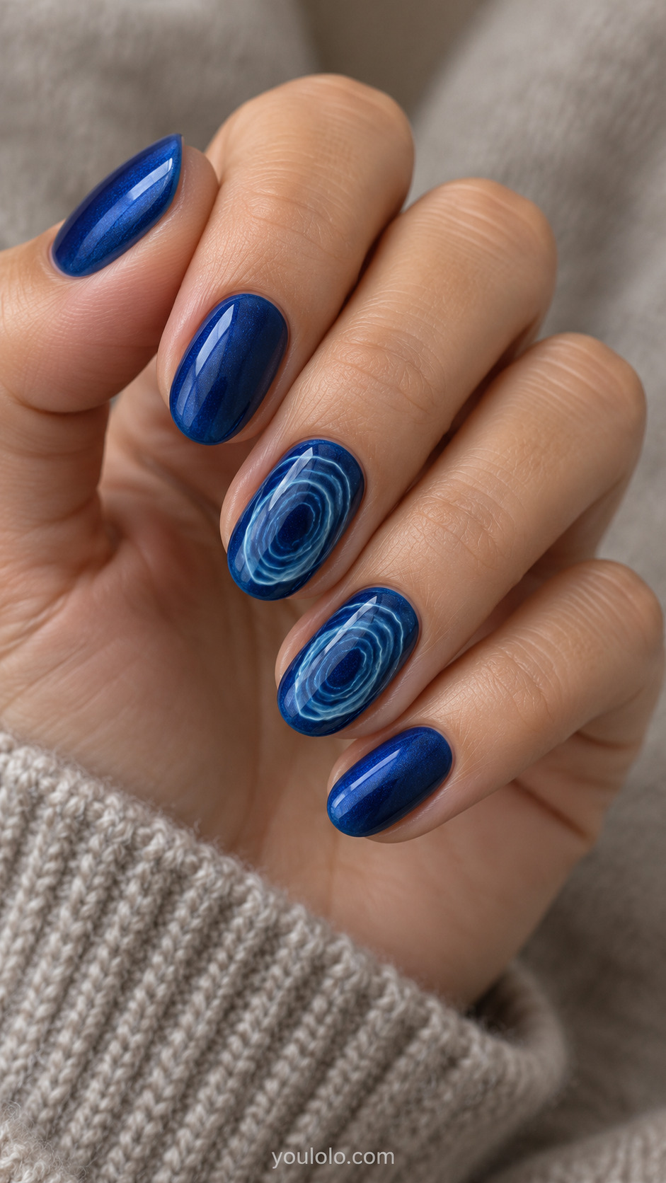 Sapphire Blue Water Ripple Art on a softly gathered feminine hand with detailed sapphire blue manicure