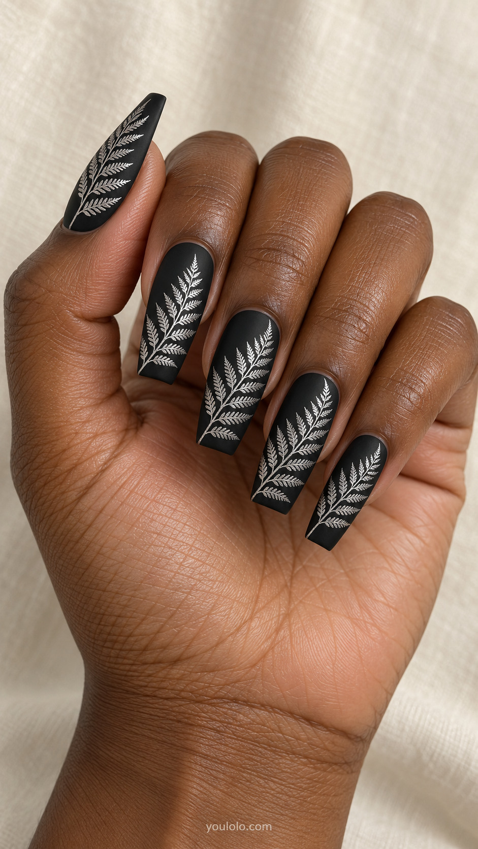 Long tapered square matte black nails finely detailed silver fern frond outlines sweeping diagonally, fine delicate leaflets, no thorn branches