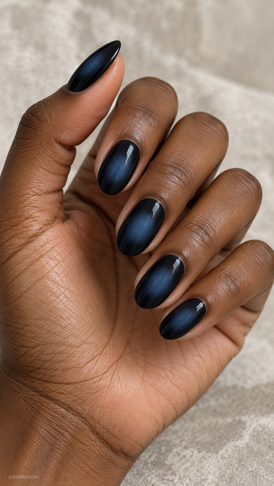 A Smoky Blue Aura Center on a naturally posed hand, showing dark blue polish and detailed nail art