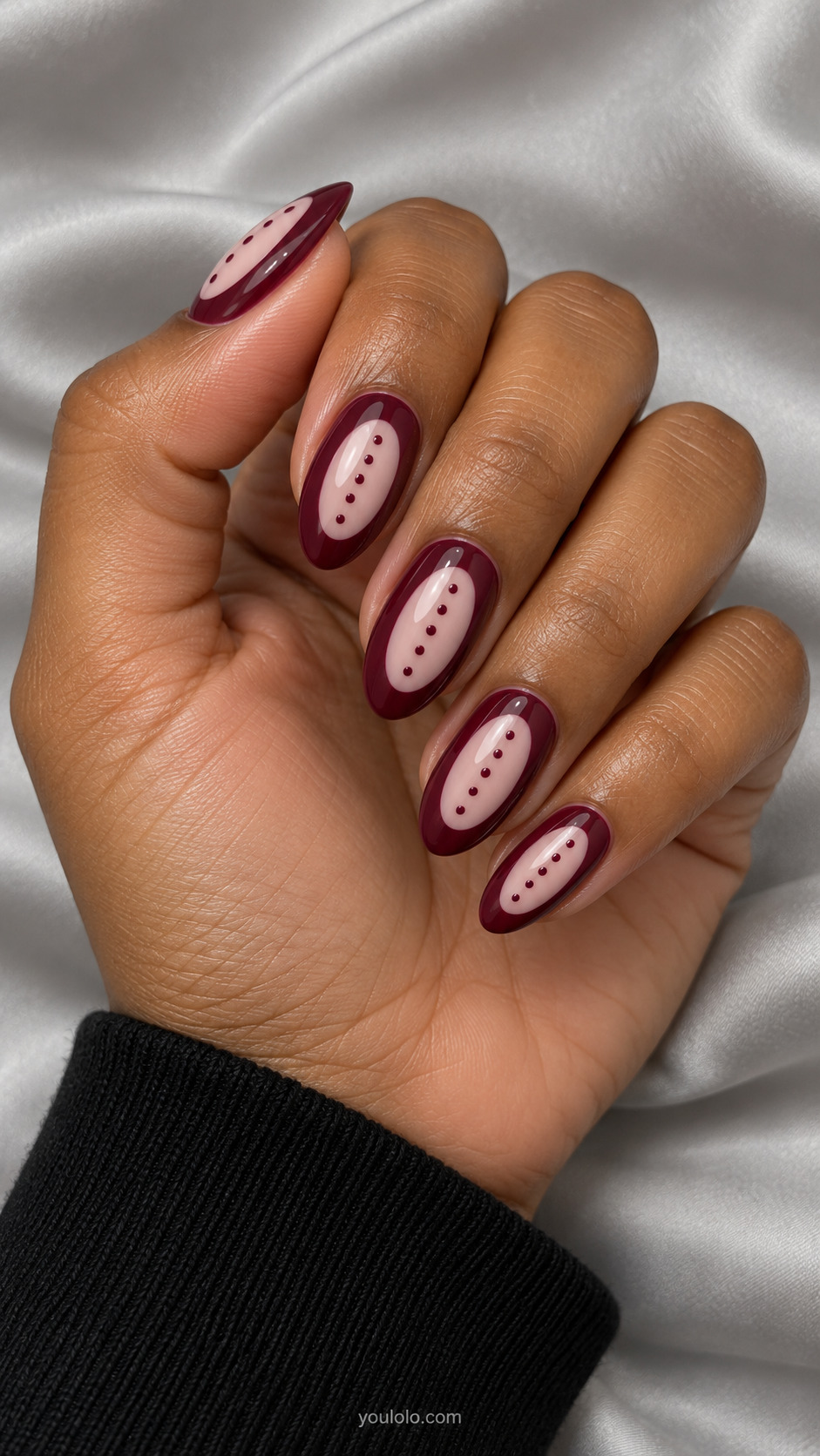 Medium almond burgundy nails with elongated blush oval inset centered each nail containing tiny burgundy dots; broad wine border plain.