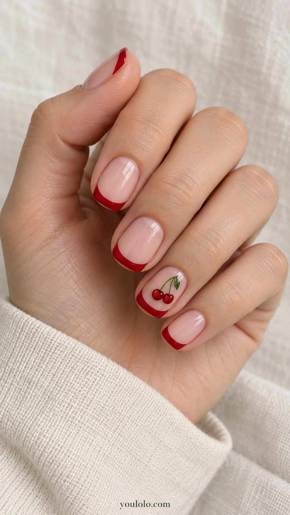 short squoval nude nails, red French tips on four nails, ring nail has two miniature red cherries green stem and matching red tip on a naturally gathered hand