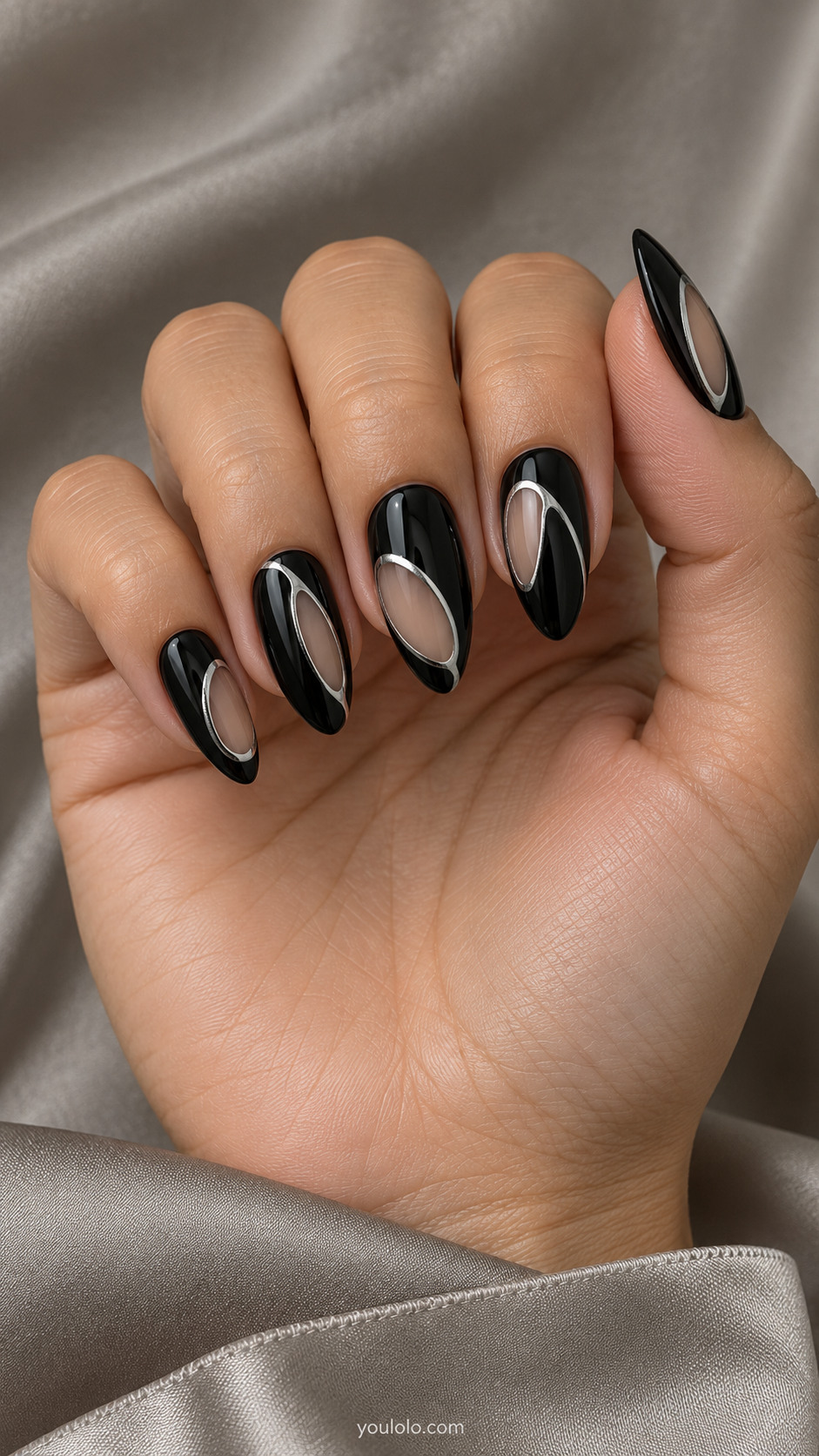 Medium almond glossy black nails metallic silver thin oval outlines around elongated clear nude openings placed offcenter, restrained sculptural modern graphic