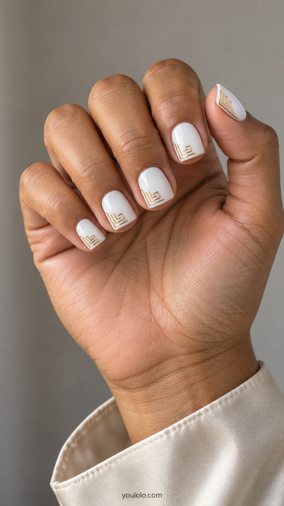 Short square white nails with a fine stepped gold maze in one corner of each nail