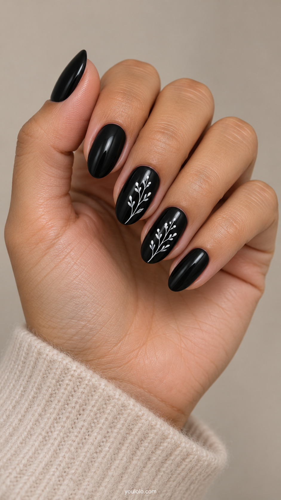 Glossy black oval nails with fine white botanical sprigs