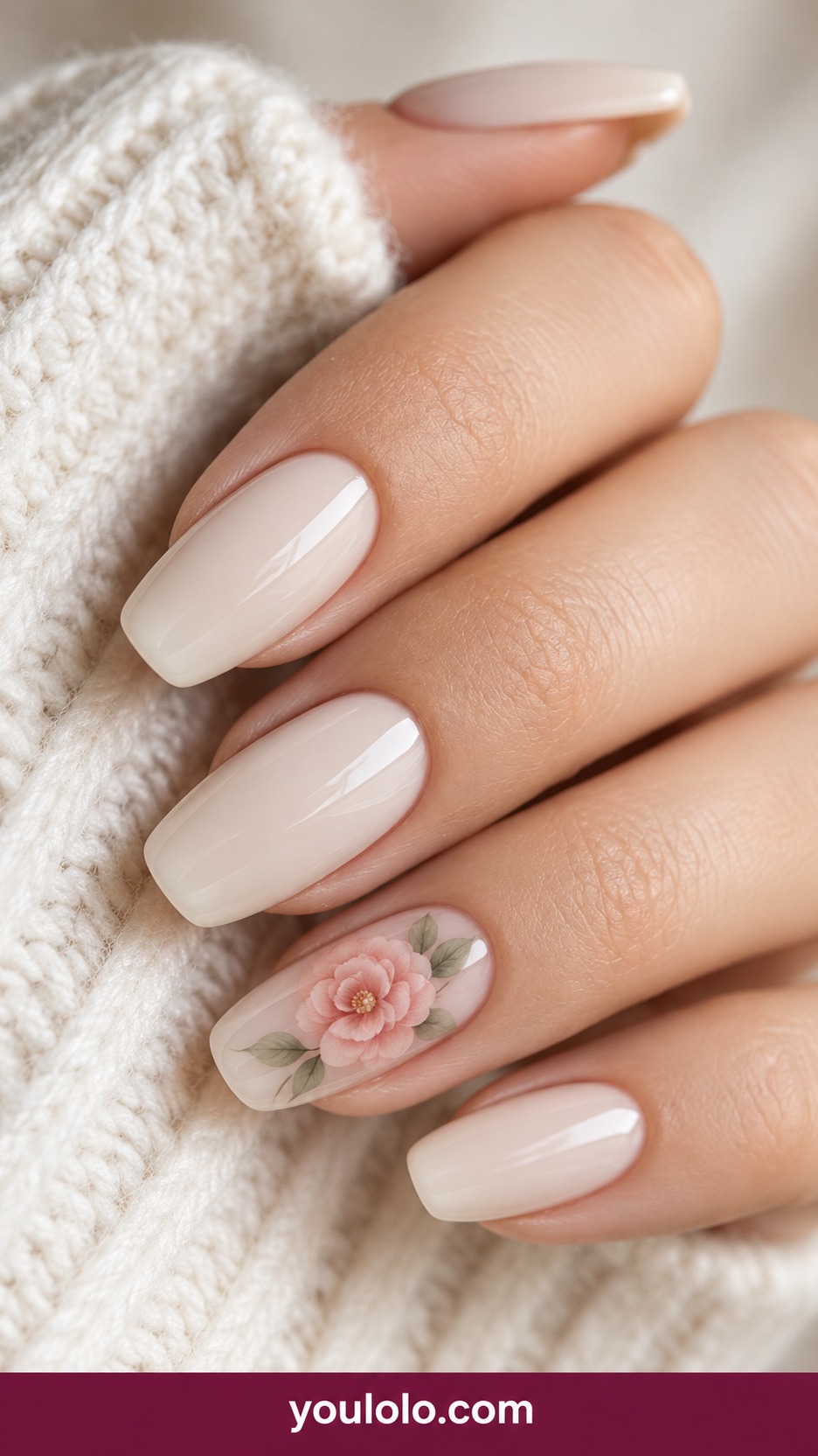 Medium squoval warm ivory nails one accent fine blush painted camellia with two pale sage leaves, others solid glossy ivory on a naturally curled young adult hand