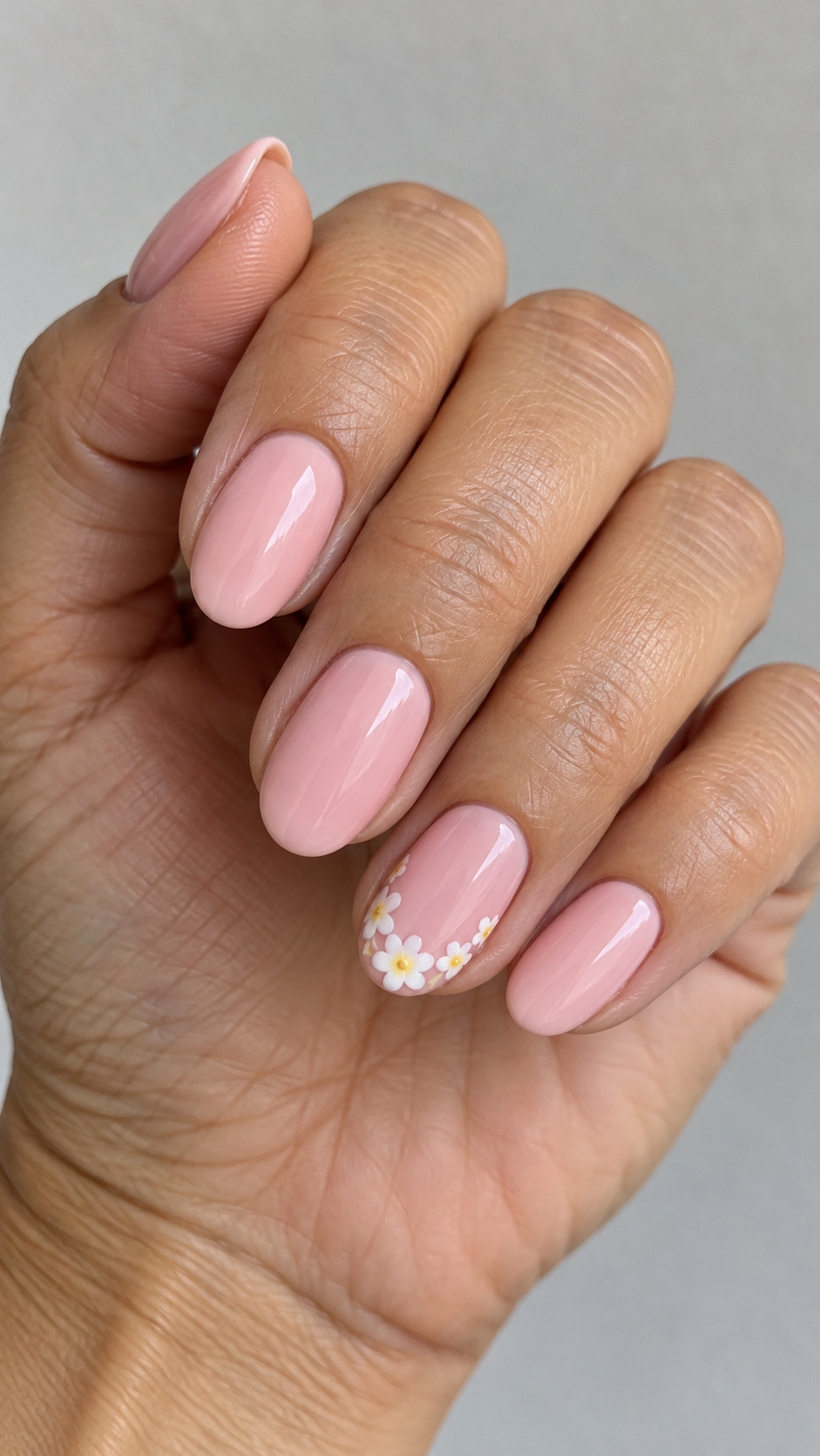 Pink with a Flower French Accent: Baby pink oval nails with a white flower border on the ring nail's tip on a naturally posed adult hand