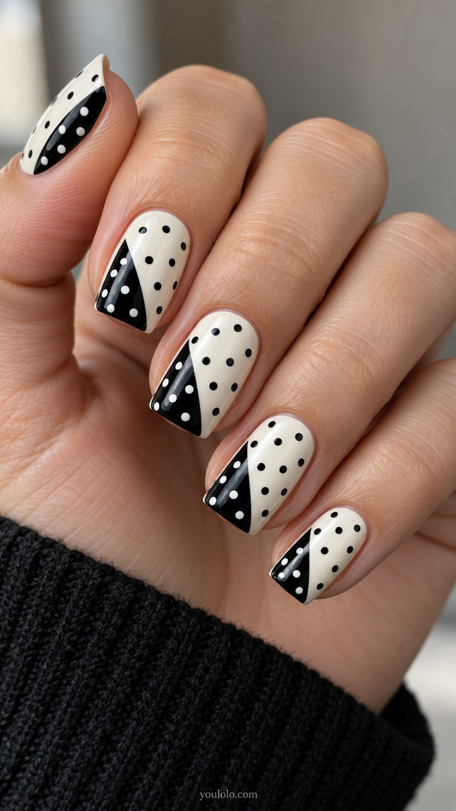 Medium square ivory nails with black triangular fold shape entering from free edge one side, white dots on black triangle and black dots on remaining ivory, same scale