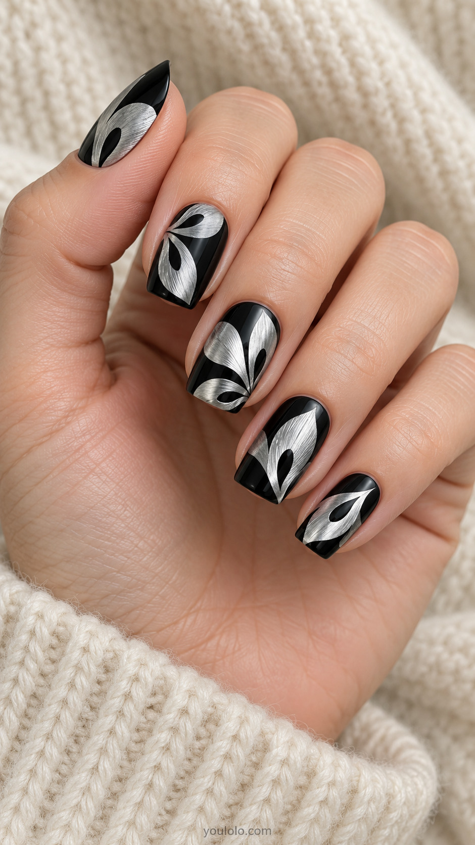 Medium square black nails oversized flat brushed-silver abstract petal silhouettes at different diagonals with clean black teardrop cutouts inside each, modern graphic botanical art