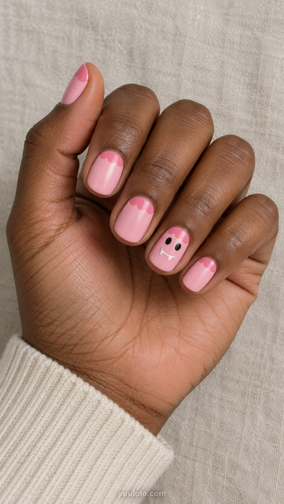 Short pink nails with darker scalloped cuticles and a small white-fanged face
