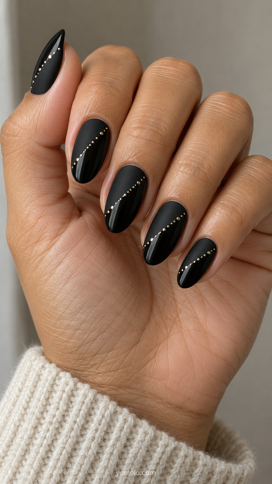 Almond nails with diagonal matte and glossy black sections divided by gold dots