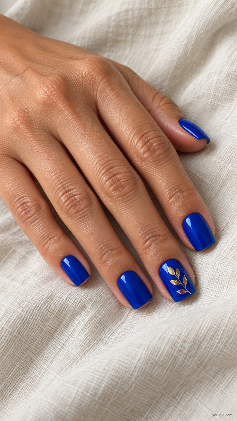Royal blue square nails with a delicate gold leaf sprig on one nail