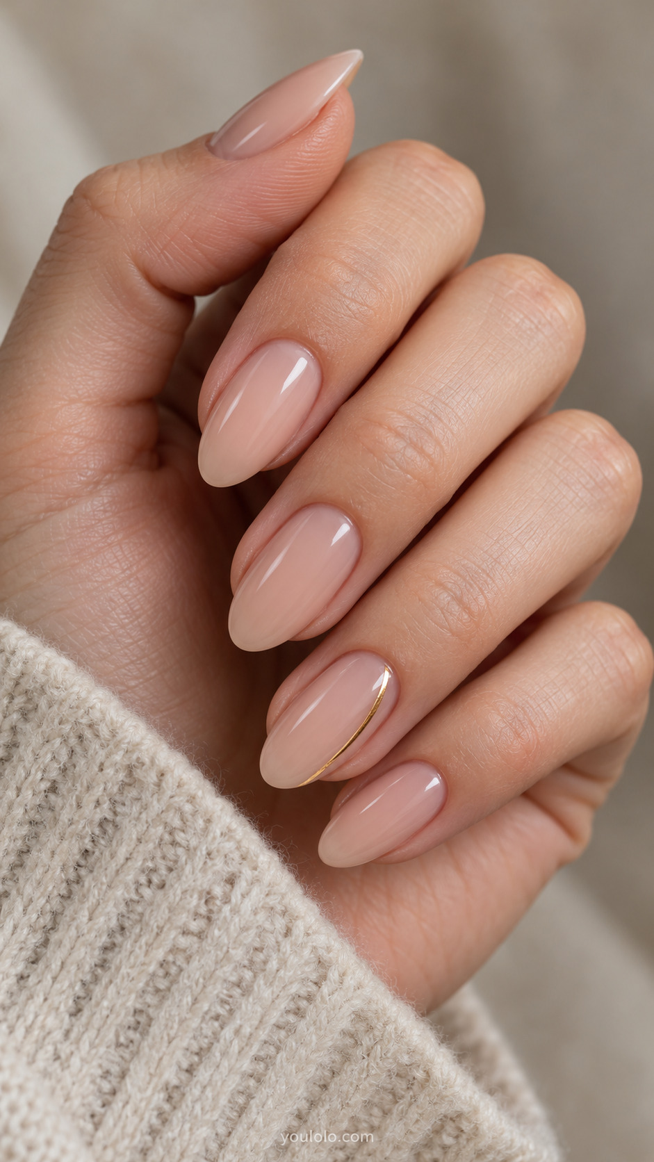 Medium almond warm nude nails with a fine gold stripe along the side of the ring nail.
