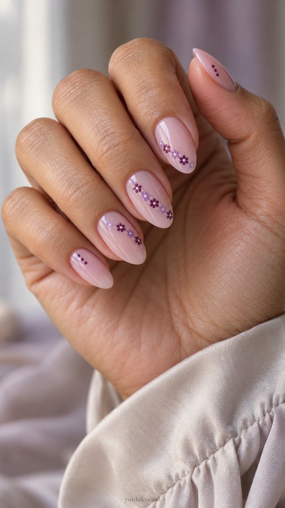 Sheer lilac almond nails with diagonal daisy chains and plum micro dots.