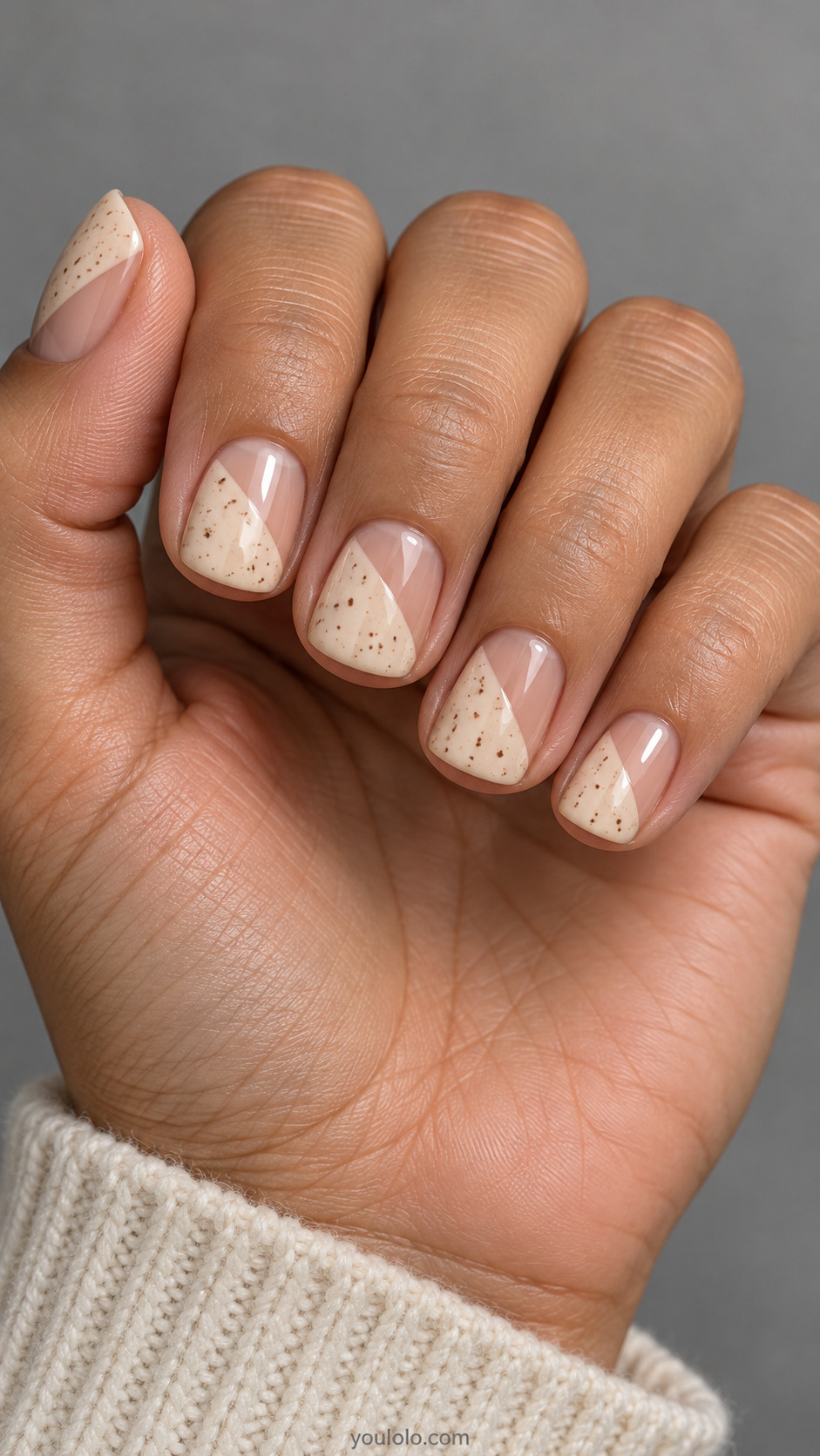 Short square nails: each nail half warm cream half sheer beige divided diagonally, tiny sparse cocoa speckles only in cream half.