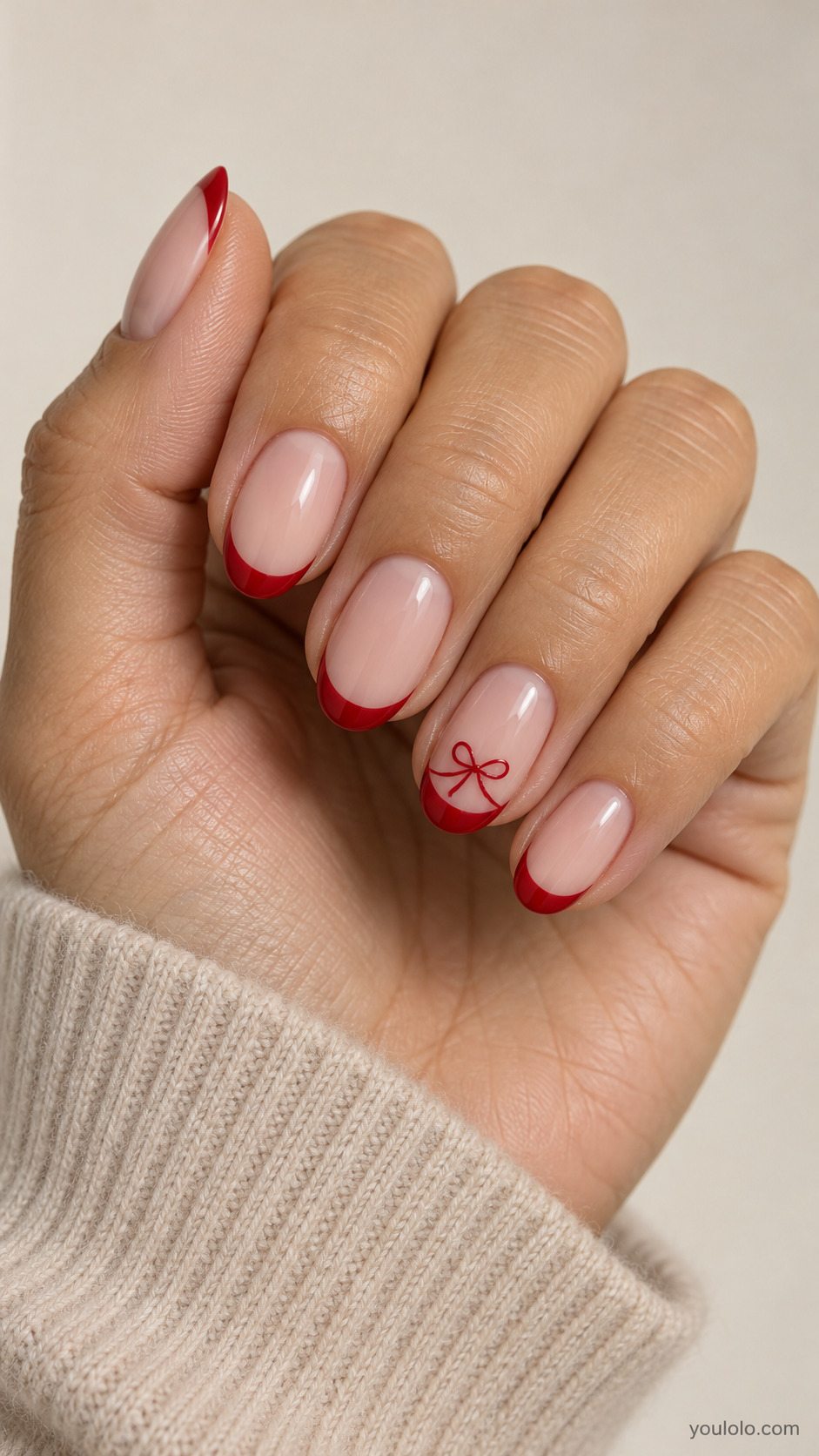 medium oval sheer blush nails, red tips on all nails, ring nail has tiny handpainted red ribbon bow below smile on a naturally gathered hand