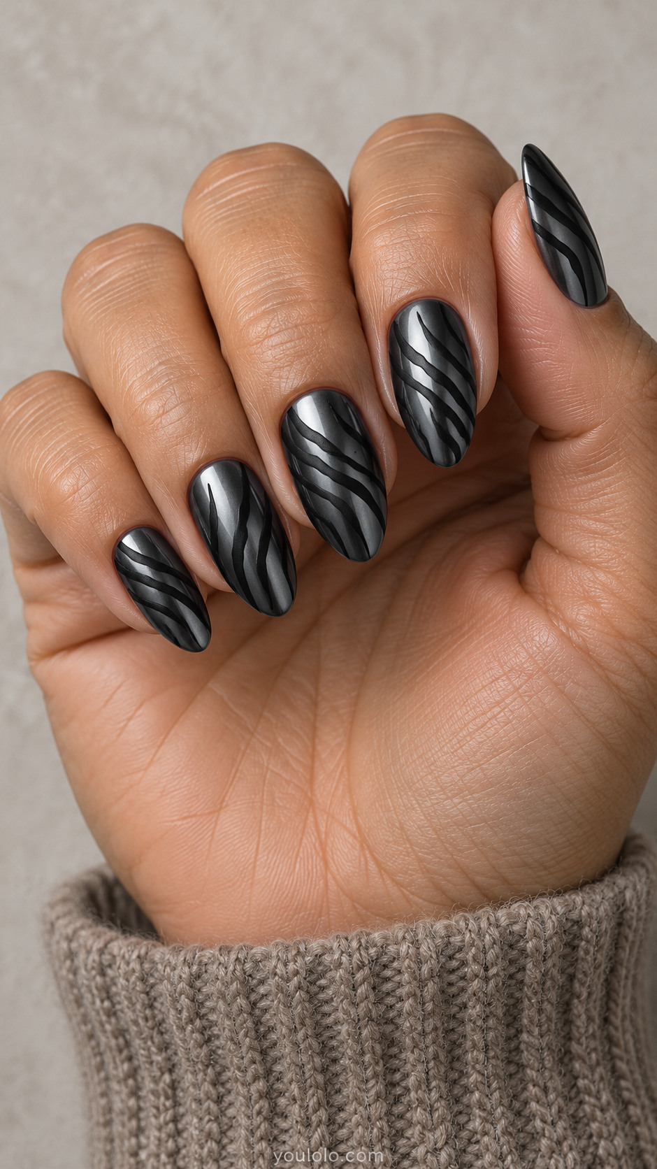 Medium almond dark gunmetal mirror chrome nails with thin tapered matte-black zebra stripes entering from alternating sidewalls, irregular forked stripes, no white
