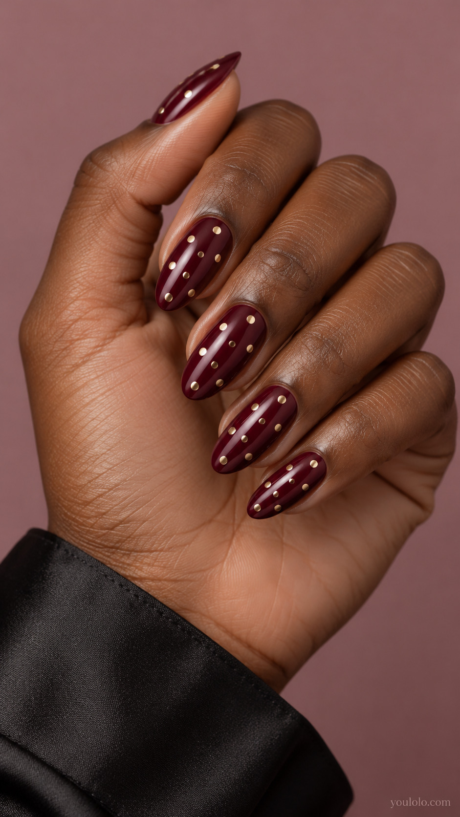 Medium almond glossy wine nails, sparse flat pale gold polished circular dots in offset rows, no rhinestones or stars.