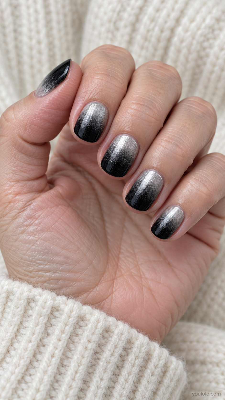 Short round nails deep black tips transitioning through graphite fine grain to brushed silver at cuticles, subtle metallic ombre no glitter no cat eye stripe