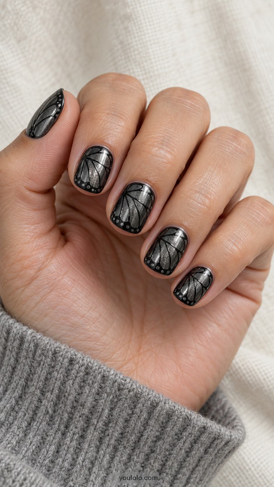 Short rounded-square gunmetal nails with black butterfly-wing veins and tiny grey dots along the dark border