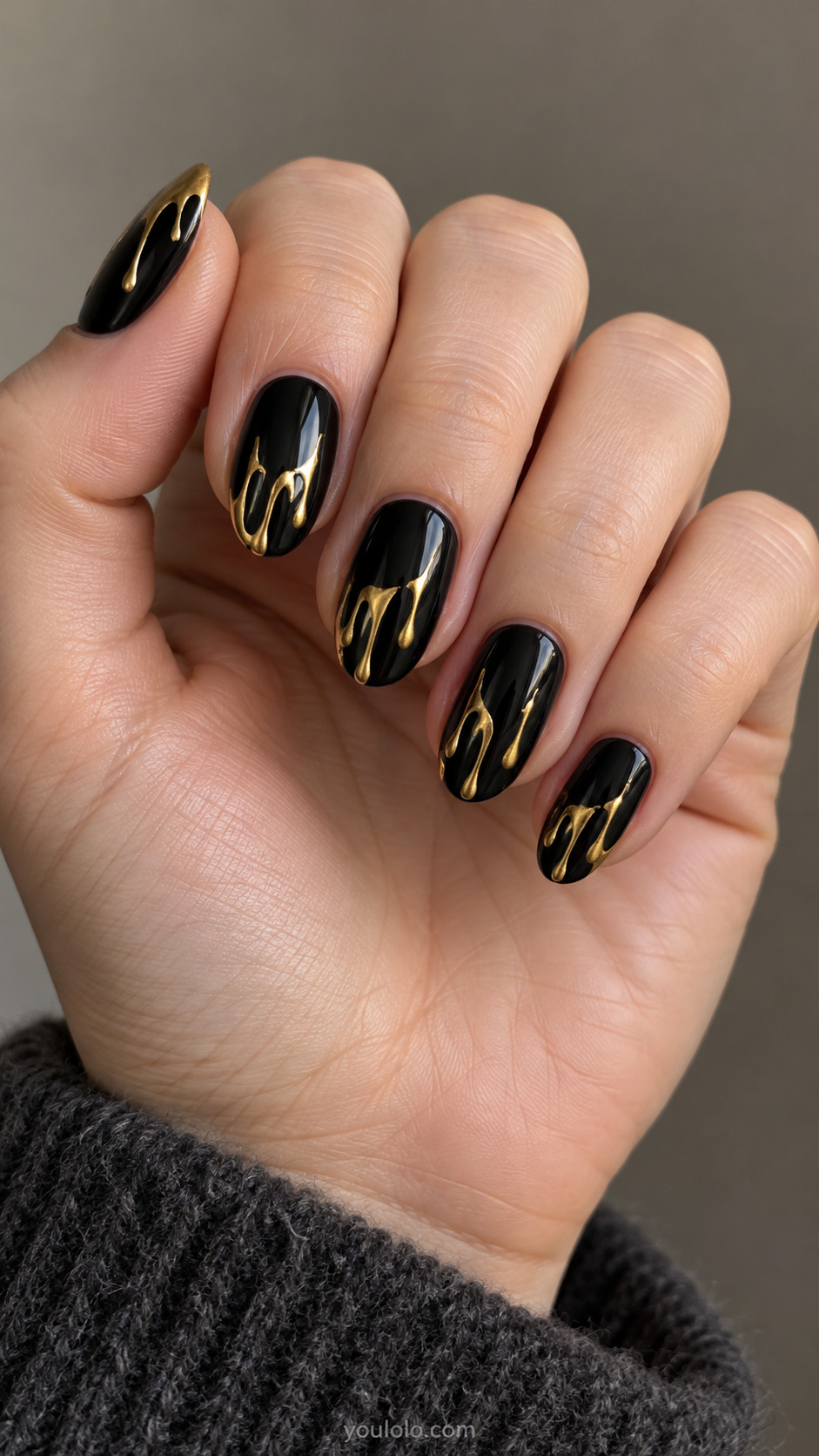 Black oval nails with slender metallic gold drips at the tips