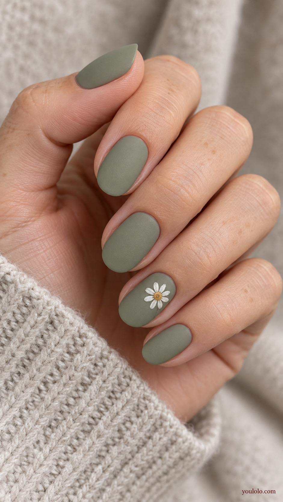 Single White Daisy on Sage on a softly gathered feminine hand with a matte green manicure