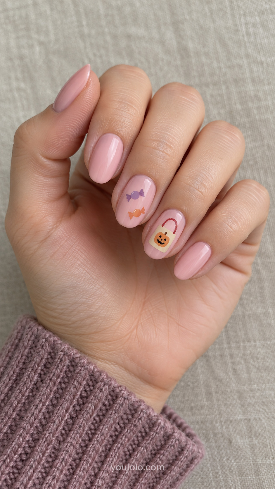 Soft pink nails with a tiny cream trick-or-treat bag and candy accents