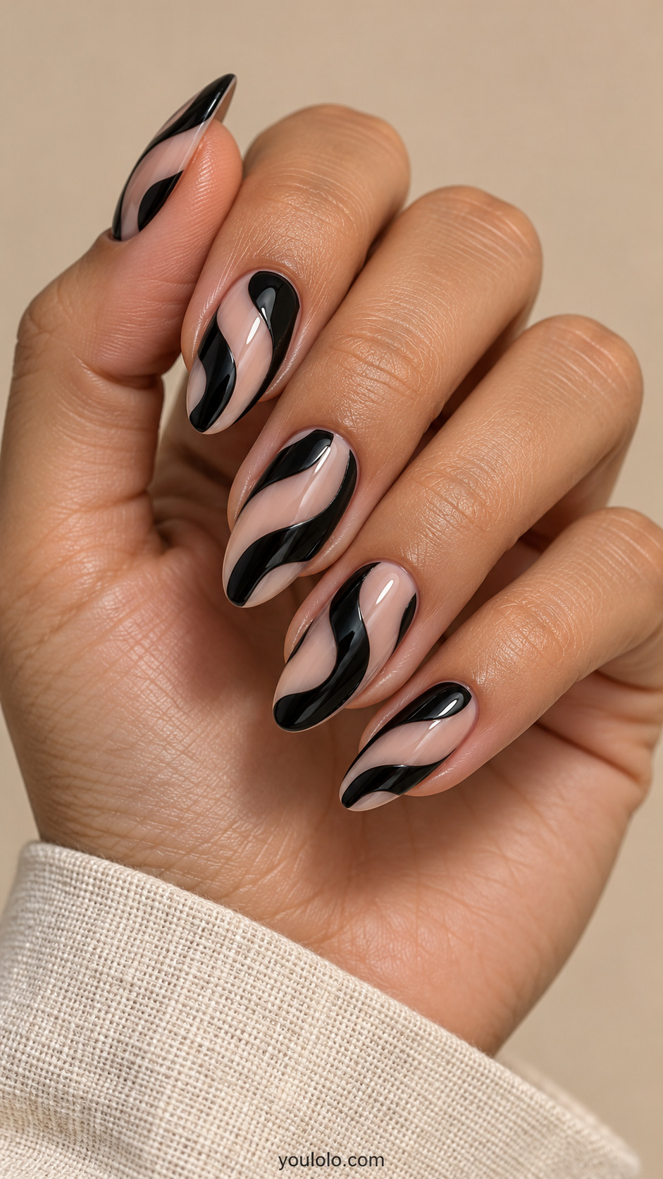 Nude almond nails with broad flowing black ribbon swirls