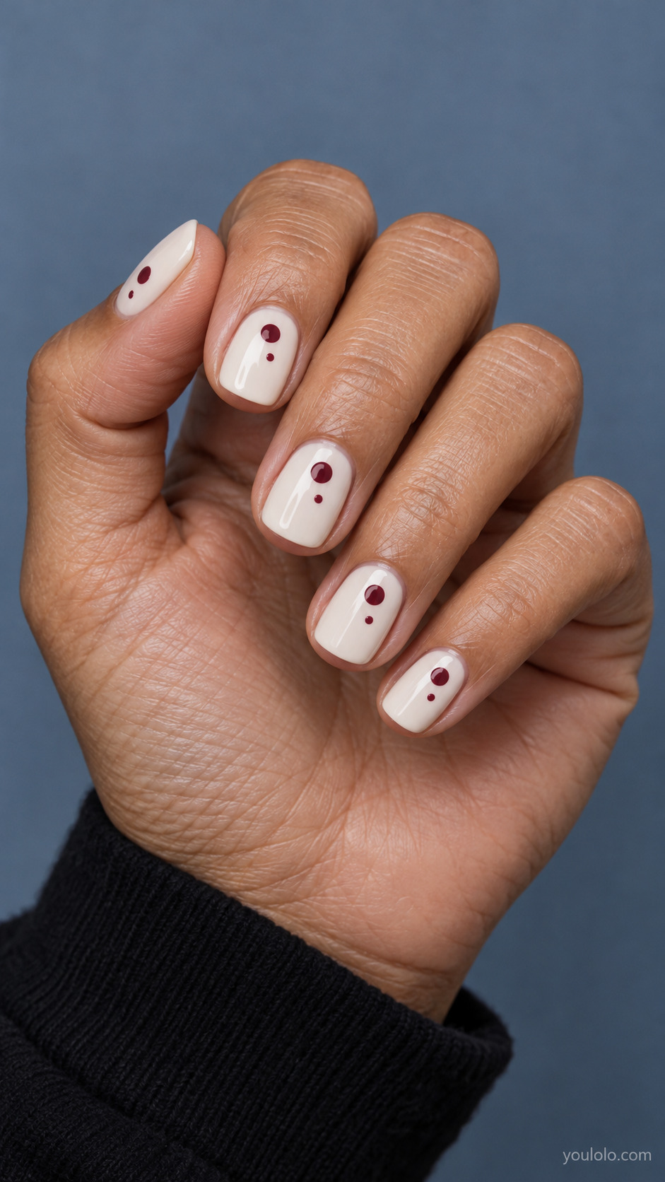 Short ivory squoval nails with one large and one small burgundy dot on each nail.